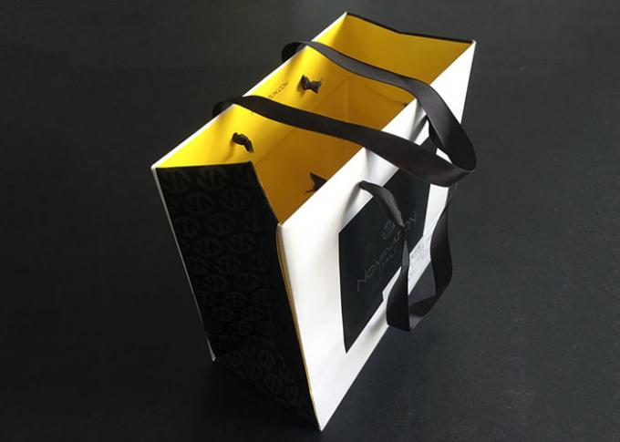 I sacchi di carta stampati regalo della maniglia del nastro portano il giallo bianco dell'interno del nero impermeabile al grasso